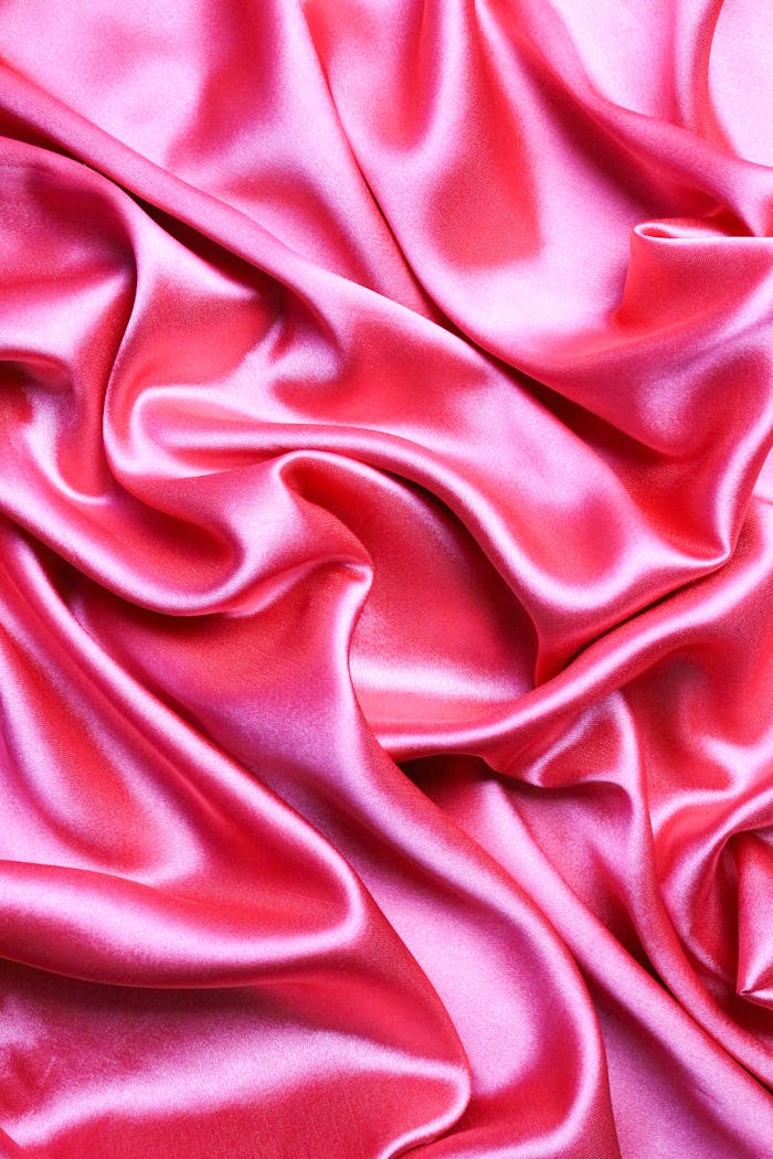 services-01 Close-up view of elegant pink satin fabric showcasing smooth and rippling textures.